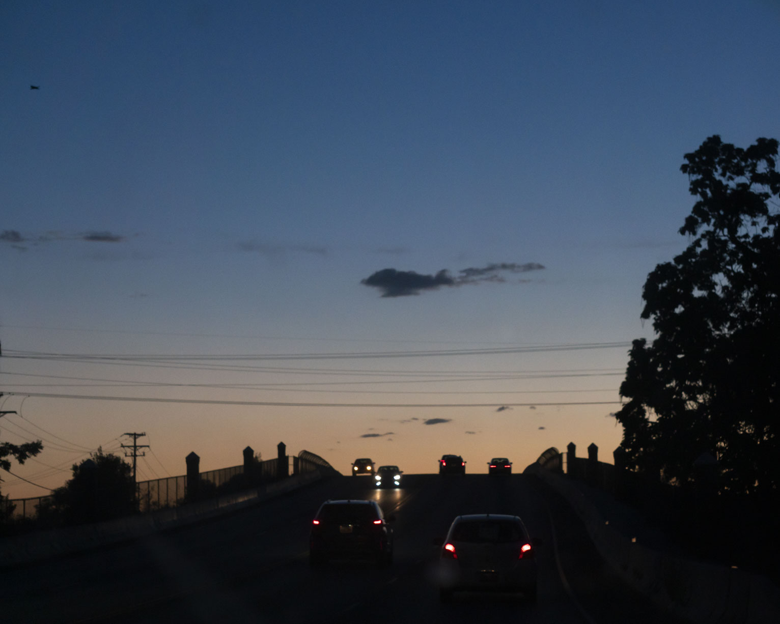 Cars go up and down the little bridge, above the sky after sunset